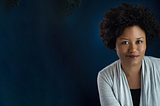 A professional portrait of Bridget R. Cooks sitting in front of a navy background