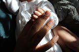 Newborn baby holding her mother’s finger