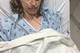 Photo of Ashley in a hospital bed with various tubes coming out of her.