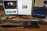 Large monitor next to a Macbook Pro laptop with a keyboard and mouse setup.