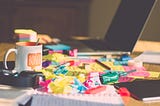 A messy desk with lots of colourful post it notes, a laptop and a mug. (Not my desk) Photo: Ferenc Horvath on Unsplash