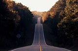 A long highway road with trees on the side