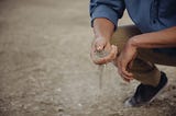 A person sifts through dry soil