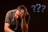 Man slumped forward, head in his left hand, with three question marks alongside him.