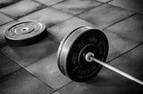 Olympic bar with bumper plates set on the ground in a gym setting.