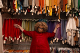Ruth Carter leaning against a backdrop of colorful costumes on racks