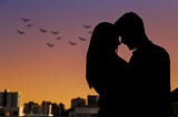 Black sillouette of a heterosexual couple against a dusky sky of orange and purple with birds. She has long hair, their foreheads are touching, they are embracing. Classic fairytale romance… or is it?