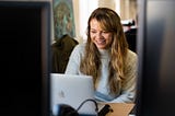 A female looking at her laptop and smiling.