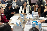 Young people sitting around a table with papers and water bottles.