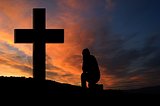 Someone kneeling in front of a Cross