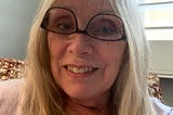 Blonde author, smiling while wearing her glasses upside down.