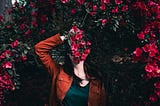 A woman hold flowers in front of her to hide her face.