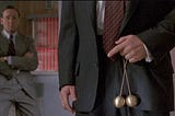 Scene from the movie Glengarry Ross — Alec Balding holding brass balls in front of his pants.