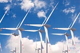 Double windmills that look too good to be true against a bright blue sky with fluffy white clouds