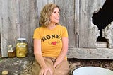 Woman sitting in front of an old barn smiling.
