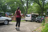 a woman jumping rope on a driveway