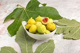 Fig fruit in a bowl surrounded by fig leaves
