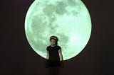 A little girl with a huge moon image at the background