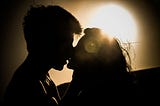 A backlit couple kissing