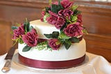 White wedding cake with red flowers.