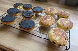 Welsh griddle cakes on a cooling rack, the left lot burnt black.