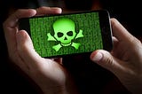 A smartphone held in hands showing a green colored skull and bones symbol.