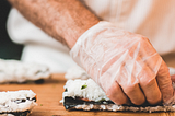 chefs hands wearing vinyl disposable gloves rolling sushi