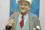 English Painter David Hockney dressed in green & blue tonal outfit with red tie.
