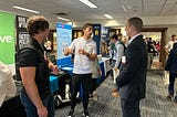 Three men talk to another during a career fair.