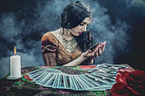 A psychic has tarot cards fanned out in front of her as she examines the one in her hand