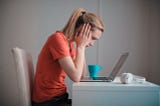 Woman with a stressed look on her face looking at a computer.