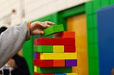 Person stacking colorful blocks on top of each other.