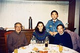 Chinese dinner with three people seated and one boy behind