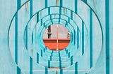 Blue, metal structures with round holes, with orange beam in the background.