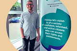 Alsdair from Advice NI standing next to a pop-up banner of Advice NI