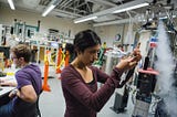 A student examines a piece of equipment in a lab as steam pours from a device nearby.