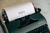 An antique typewriter with a written “2021” paper