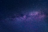Photo of the Milky Way as seen from Earth in the night sky, in shades of blue and purple