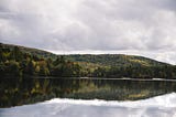 Clouds, forested hills, and a lake.