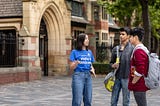A student ambassador chats with two students outside of the Great Hall.