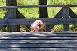 Little girl screaming with her head through the rail of a terrace.