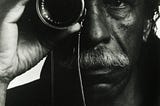 Elderly Gordon Parks holding a camera lens up to his eye