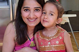 Neha stands in her kitchen next to her adorable daughter!