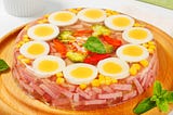 Geletin salad with eggs, ham and vegetables on a plate