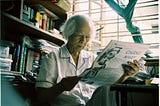 Nguyen’s grandfather reading a newspaper in writing corner, surrounded by books and papers.