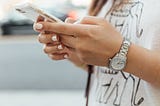 A young woman looking at a phone in her hands.