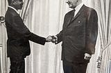 Eric Springer, a young Black man shakes the hand of Lyndon Johnson. He is a new advisor on the Human Rights Commission.