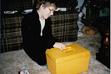 The author at 12 or 13 years old, sitting on the floor with a large yellow plastic box in front of him