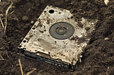 An old hard disk half-buried in the dirt