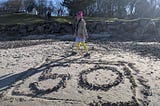 Suzi Mapes, the author’s daughter, on the beach infront of a number 50 made out of pebbles.